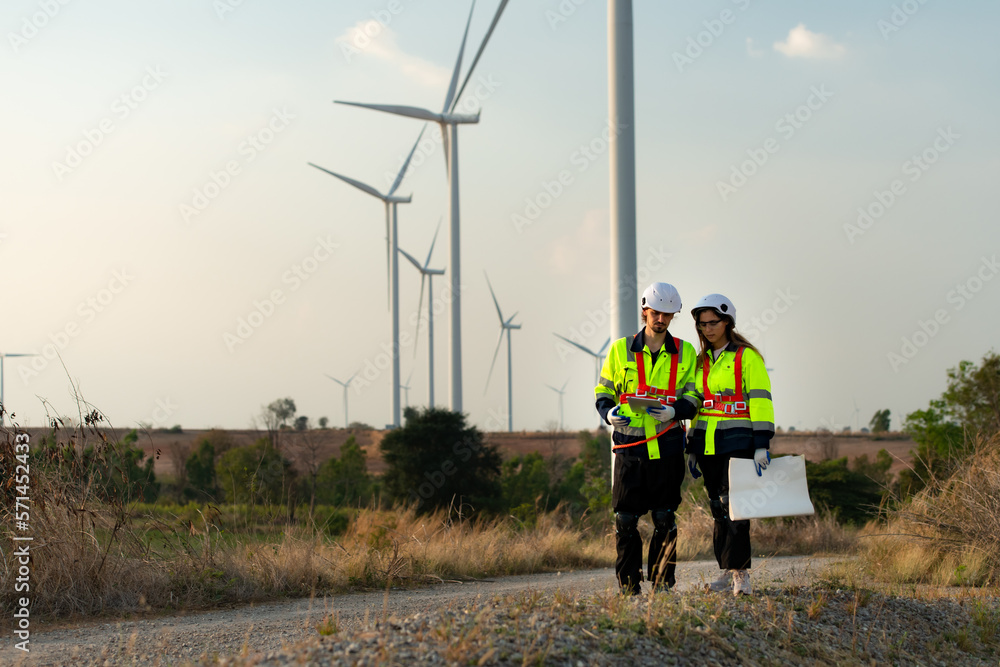 Man and female engineer stationed at the Natural Energy Wind Turbine site. with daily audit tasks of major wind turbine operations that transform wind energy into electrical electricity Man and female engineer stationed at the Natural Energy Wind Turbine site. with daily audit tasks of major wind turbine operations that transform wind energy into electrical electricity