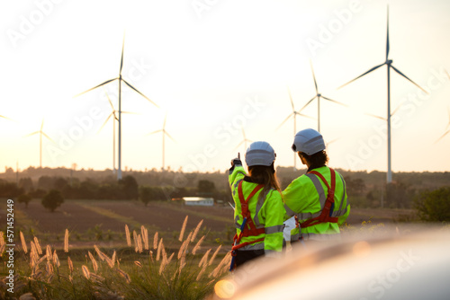 Engineers working on wind farms for renewable energy are responsible for maintaining large wind turbines. Review all tasks of the day while the evening sun shines a beautiful golden light 