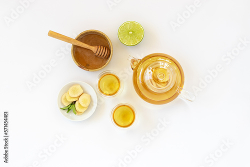 Top view of a cup of tea with ginger root, lime, cinnamon and teapot on white background. Health drink concept.