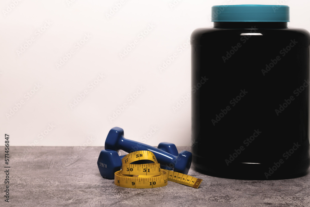 Obraz premium close-up of a Whey protein powder, dumbbells and measuring tape