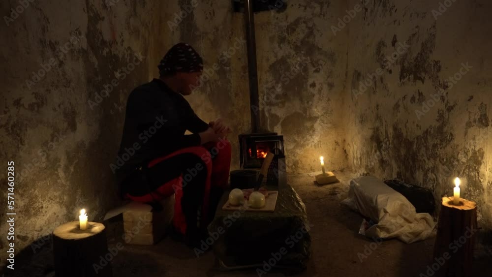 The guy in the abandoned hut is going to cook. There are products on the folding table. There are candles around the edges, creating a cozy atmosphere. A fire is burning in the camp stove. The guy in the abandoned hut is going to cook. There are products on the folding table. There are candles around the edges, creating a cozy atmosphere. A fire is burning in the camp stove.