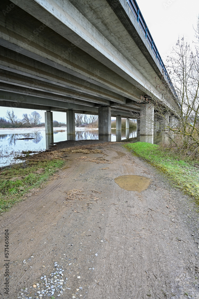 Autobahnbrücke von unten mit Betonpfeiler und Spiegelung im Wasser des Hochwassers, bei Schweinfurt Autobahnbrücke von unten mit Betonpfeiler und Spiegelung im Wasser des Hochwassers, bei Schweinfurt