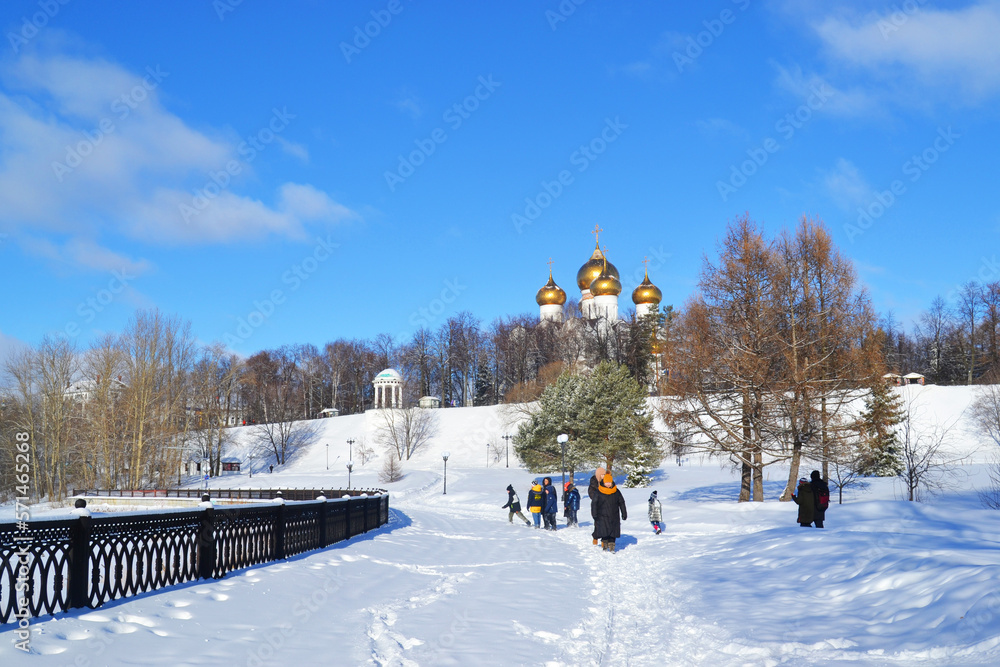 People walk along the snowy embankment of the Volga River in Strelka Park