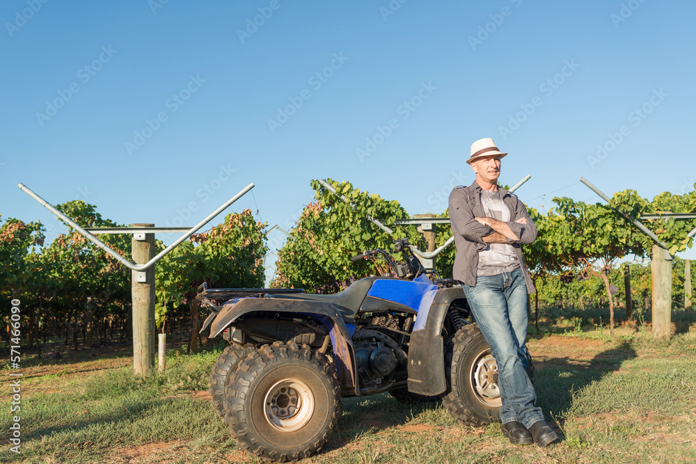 Fototapeta premium Winemaker in straw hat standing near quad bike