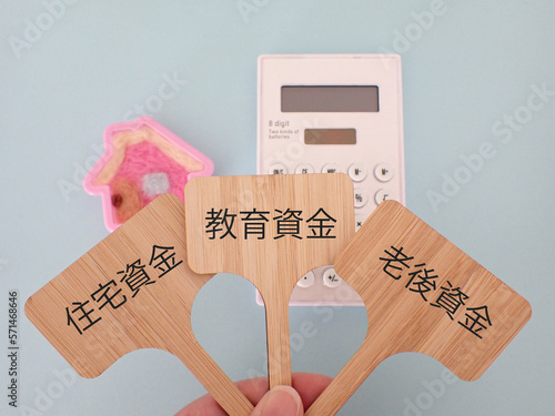 プラカードに住宅資金、教育資金、老後資金の単語、電卓と可愛い家