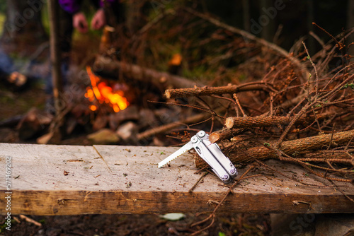 Folding pocket saw. A saw, branches and a fire. Breeding fire in nature. Cut branches for the fire. photo