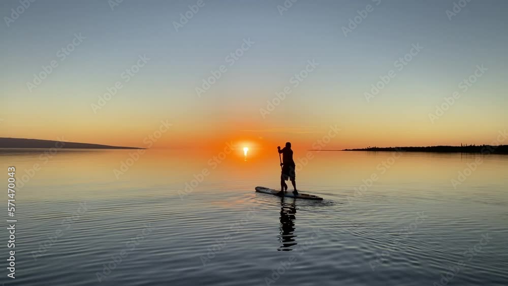 Paddle boarding with a sunset backdrop on a pristine ocean. Maui, Hawaii USA Paddle boarding with a sunset backdrop on a pristine ocean. Maui, Hawaii USA