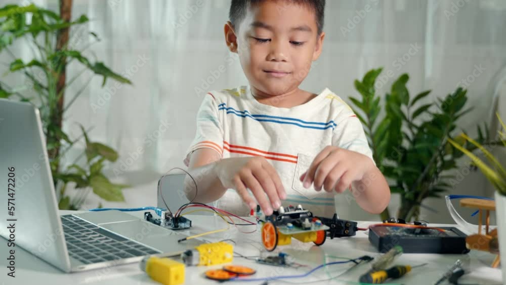 Asian kid boy assembling board into Arduino robot car homework, Little child assemble DC to DC converter into car toy, creating electronic AI technology workshop online school lesson Asian kid boy assembling board into Arduino robot car homework, Little child assemble DC to DC converter into car toy, creating electronic AI technology workshop online school lesson