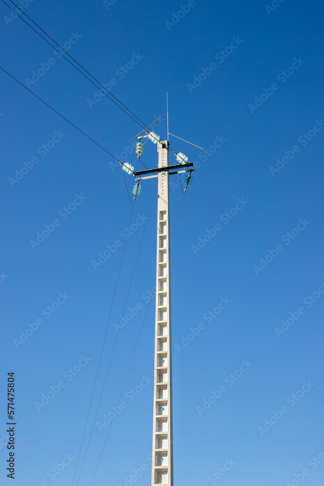 A concrete power pole on a blue sky background