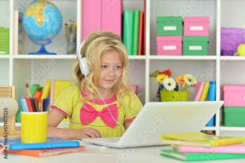 girl in headphones ding with laptop sitting at desk