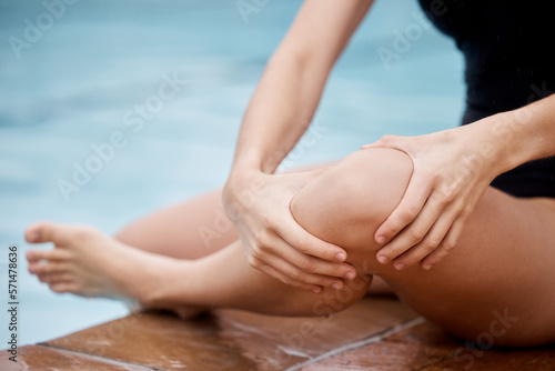 Hands, knee injury and swimming pool with a woman holding her joint in pain after a sports workout. Fitness, water and anatomy with a female swimmer suffering from an injured leg during exercise