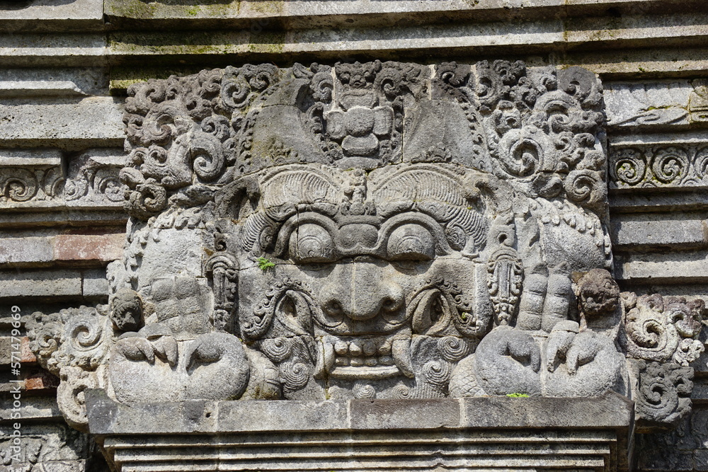 The relief of kala kirtimukha on penataran temple. Kala kīrttimukha is the name of a swallowing fierce monster face with huge fangs and a gaping mouth The relief of kala kirtimukha on penataran temple. Kala kīrttimukha is the name of a swallowing fierce monster face with huge fangs and a gaping mouth