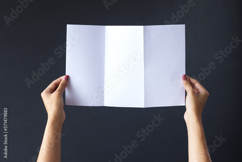 hands holding blank opened tri fold flyer brochure on gray background as template for design presentation, showcase, etc. photo