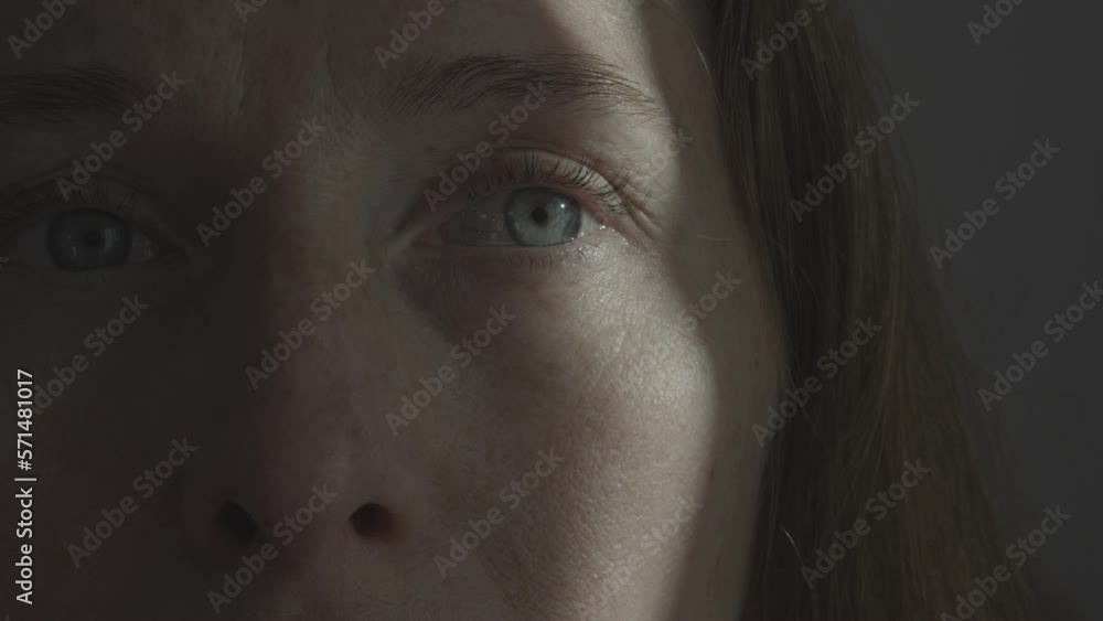 Portrait of a woman with a streak of sunlight across her eye and cheek. Psychology and psychiatry. Fear of the environment. Portrait of a woman with a streak of sunlight across her eye and cheek. Psychology and psychiatry. Fear of the environment.
