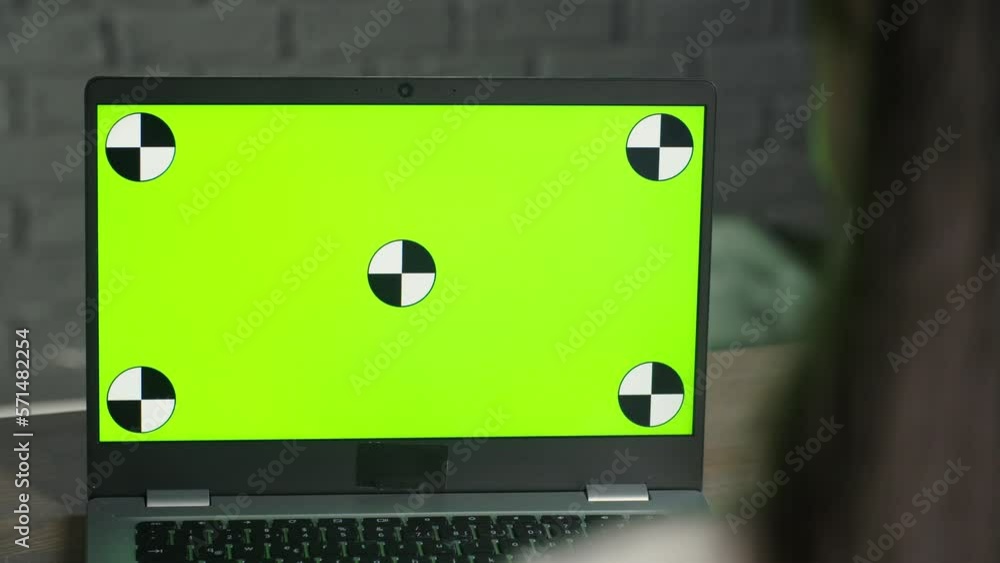 A brunette girl is sitting in front of a laptop with a chroma key. Computer with green screen. Remote work, e learning A brunette girl is sitting in front of a laptop with a chroma key. Computer with green screen. Remote work, e learning