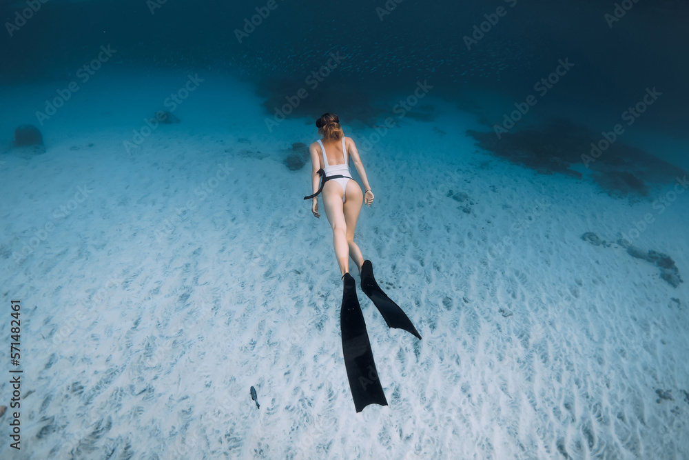 Attractive lady freediver glide underwater on the deep. Freediving with sexy woman in blue ocean