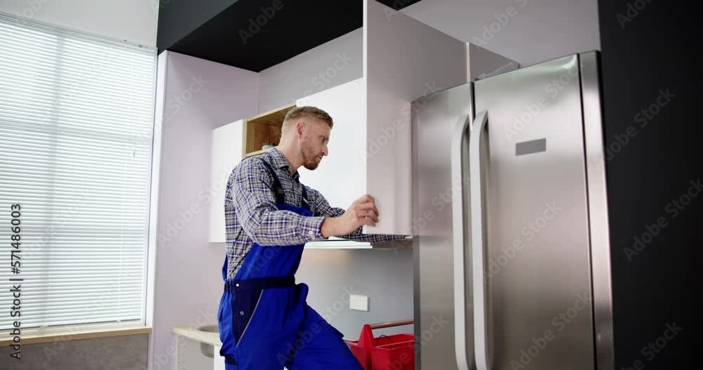 Male Carpenter Assembling White Cabinet On Wall Male Carpenter Assembling White Cabinet On Wall