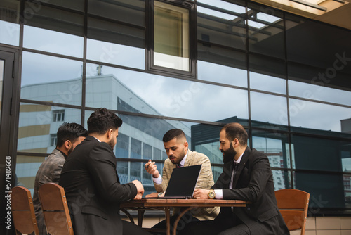 Corporate meeting of business partners outside the office. Male employees sit at the table and discuss the goals, ideas and plans of the company.