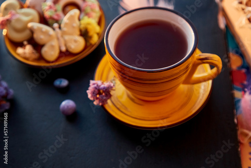 Aesthetic yellow tea cup and Easter homemade cookies with decorations. Holiday food, tea time