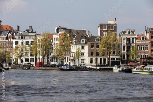 Canal  scene with a tour boat, bridges and traditional Dutch houses in Amsterdam. Netherlands