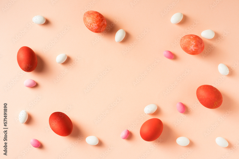 Red easter eggs with colorful candies on pink background. Blank copy space on center. Red easter eggs with colorful candies on pink background. Blank copy space on center.