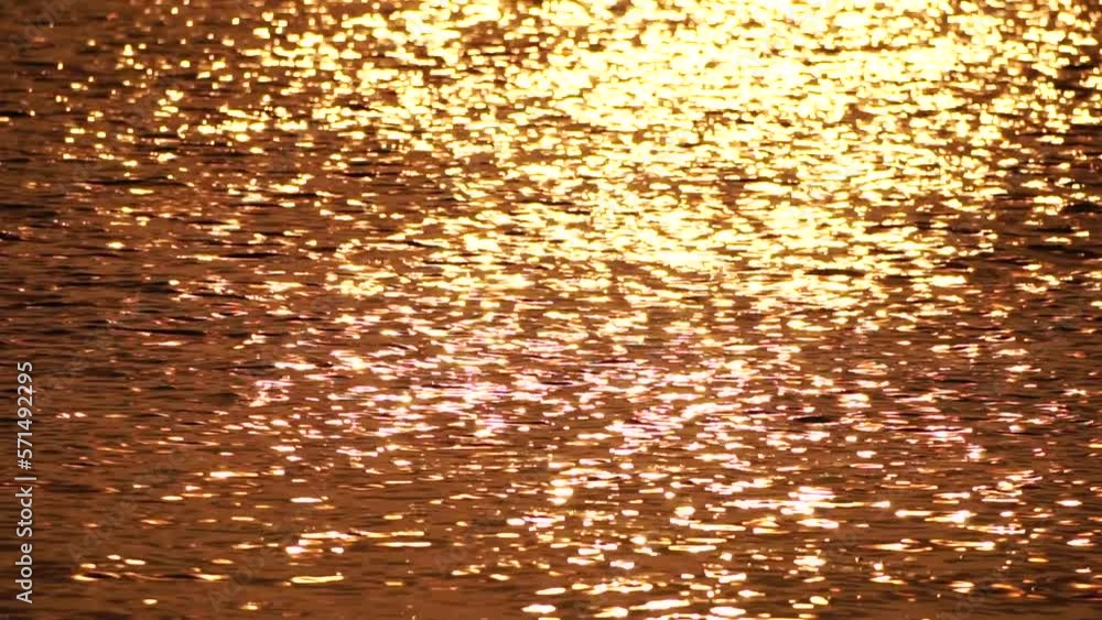Blurred golden sea at sunset. The sun reflects and sparkles on the waves with bokeh, illuminating the golden sea. Holiday recreation concept. Abstract nautical summer ocean sunset nature background. Blurred golden sea at sunset. The sun reflects and sparkles on the waves with bokeh, illuminating the golden sea. Holiday recreation concept. Abstract nautical summer ocean sunset nature background.