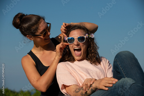 Two women laughing outside on a sunny day.
