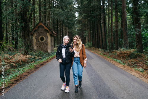 Two women walking down the road looking at their smartphone