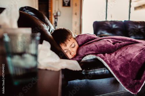 Young boy asleep on couch feeling ill photo