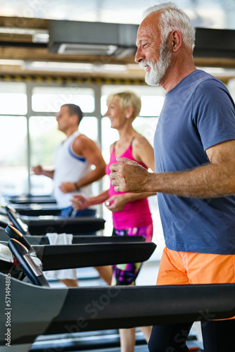 Senior fit man and woman doing exercises in gym to stay healthy