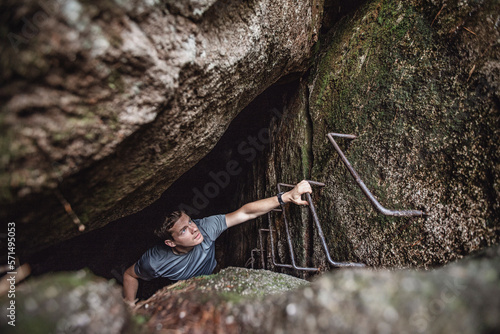 A man climbs ladder rungs out of a dark cave, Millinocket, Maine photo
