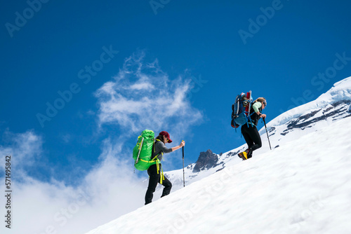 Two female mountaineers hike above cloudline on Mt. Baker, WA