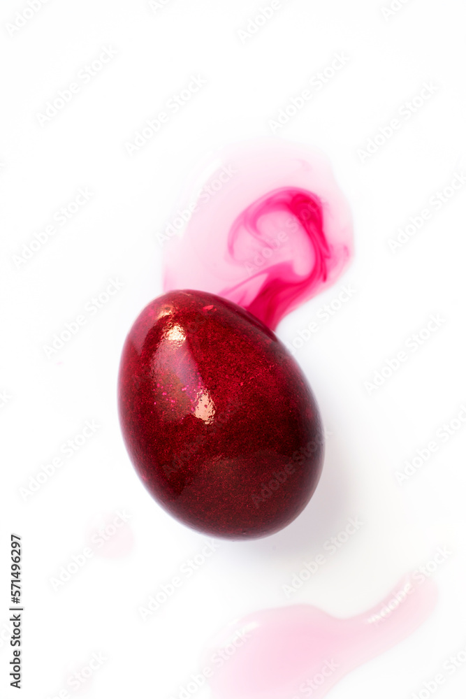 Dye purple color easter egg, isolated on white. Purple easter egg and liquid food coloring on white background. Close up shot.