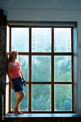 The girl is standing in the room near a large panoramic window. Free Download The girl is standing in the room near a large panoramic window. - GFXLoad
