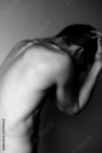 Young man holds his head with both hands. Soft focus