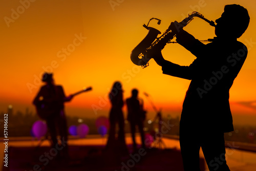 Canvas Print Silhouette saxophone musician man showing on blurry jazz trio band and sunset cityscape background