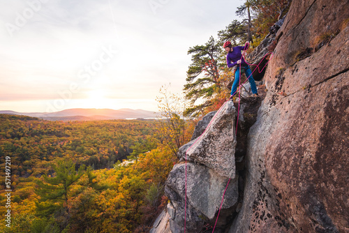 Man getting ready to rappel with mountains and foliage in background photo
