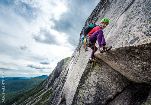 Man with tattoos climbing steep rock wall face photo