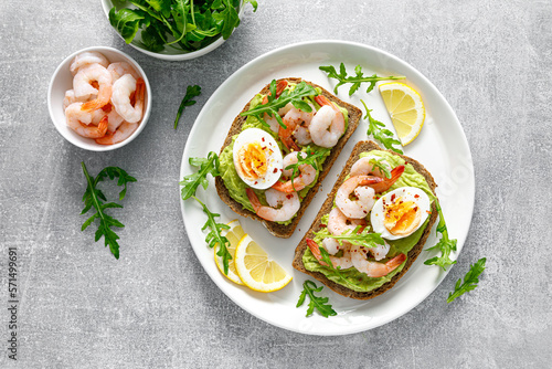 Print op canvas Toast with shrimps, avocado guacomole, arugula and boiled egg, top view