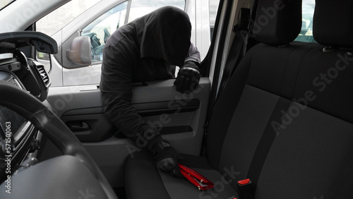 a man in a black hood steals a red wallet from a car