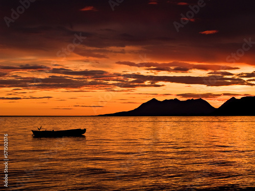 Mountains and rowboat in orange sunset in Northern Norway