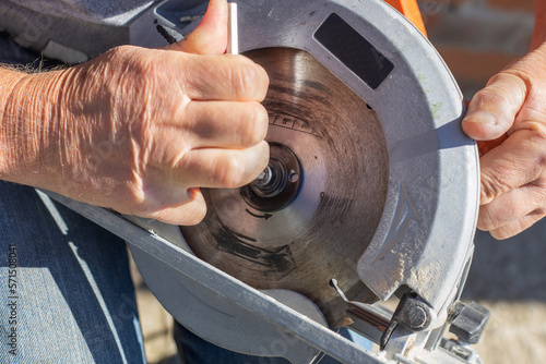 a man screws a saw blade with a hexagon on a circular miter saw