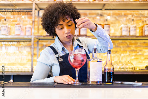 latin woman bartender preparing a cocktail on the bar counter photo