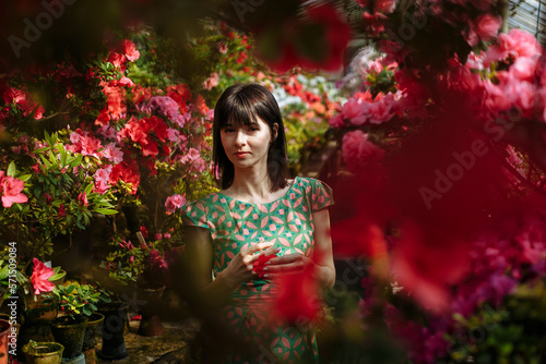 A brunette in a green dress in a garden of red flowers