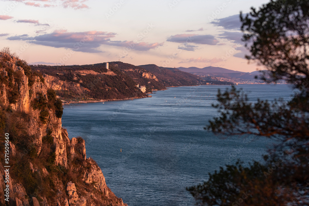 Golden sunset at the sea with rocky coastline, view to Trieste gulf