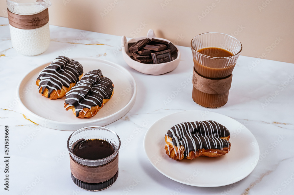 Homemade eclair in chocolate glaze on a plate. Coffee in a glass Stock  Photo | Adobe Stock