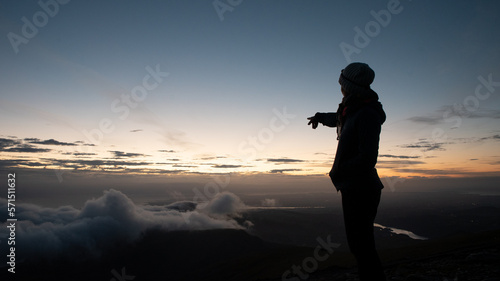 Une femme montre des nuages sur une montagne le soir
