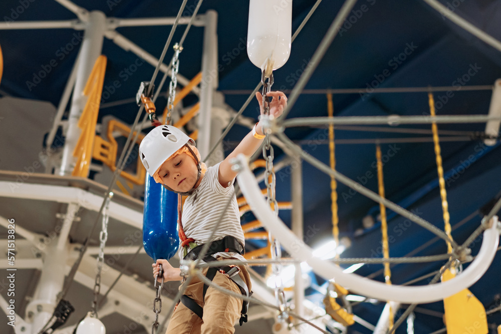 cute little boy climbing in adventure park passing obstacle course. high rope park indoors cute little boy climbing in adventure park passing obstacle course. high rope park indoors
