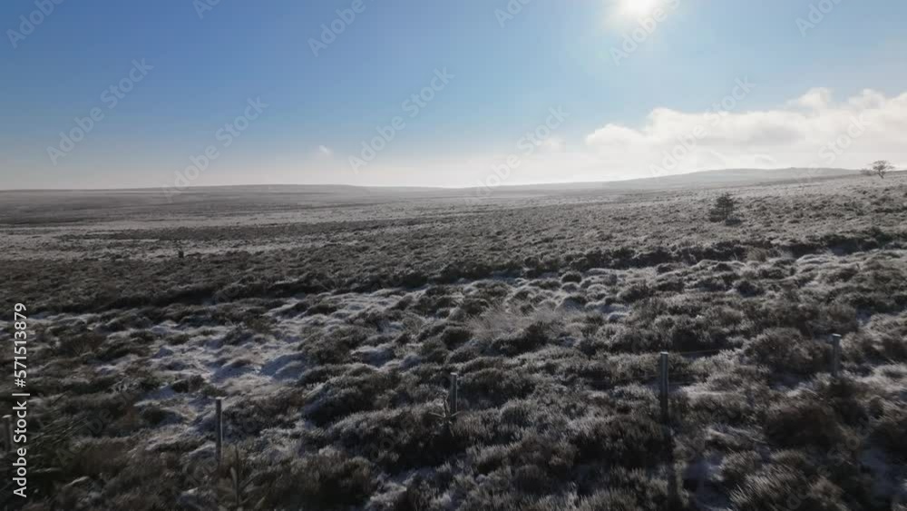 Drone flight over two men walking along a frozen, wild path, revealing a large open moorland lit by winter sunlight. Drone flight over two men walking along a frozen, wild path, revealing a large open moorland lit by winter sunlight.