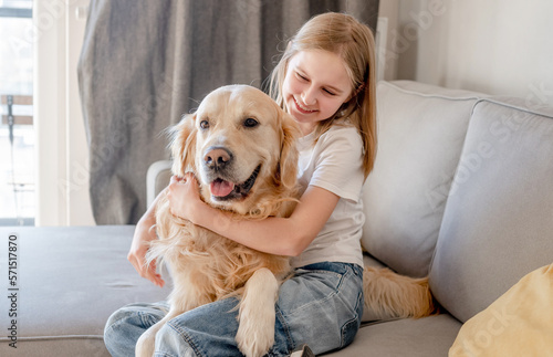 Preteen girl with golden retriever dog at home